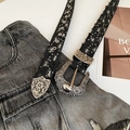 Nahaufnahme der gravierten Western-Silberschnalle an schwarzem Distressed Denim-Gürtel - Vintage-Stil mit gravierter Schnalle / Schwarz