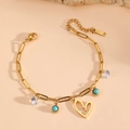 Detail of gold paperclip chain bracelet featuring a heart charm and turquoise beads - Gold Hollow Heart Bracelet (F411)