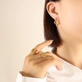 Golden star-shaped earrings and minimalist rings set worn by model on beige backdrop - Star / Gold