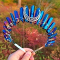 Macro shot of blue aura quartz crystals and silver crescent moon on a metal headband - Deep Blue Crystal + White K Moon