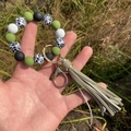 Close-up of leopard print silicone bead keychain with olive tassel on green grass - Grass Green