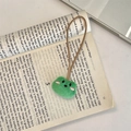 Dettaglio del portachiavi in peluche a forma di rana verde su una pagina di libro - Rana