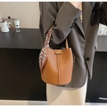 Detailed close-up of a brown woven bucket bag with a silk scarf wrapped handle - Brown
