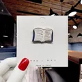 Enamel book brooch with I read banned books slogan on a white display card - 67*I Read Banned Books Pin