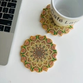 Close-up of vibrant orange and green mandala pattern ceramic coasters on a white table - Orange Gold Mandala