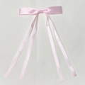 Detail of pink satin ribbon bow hair clip with four long streamers on leather background - Pink