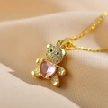 Makro-Detail des goldenen Teddybär-Anhängers mit Kristallen und rosa Herz-Edelstein - Rosa