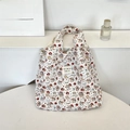 Detail of quilted white tote bag featuring cute cartoon prints and colorful logo patch - Cat Angel