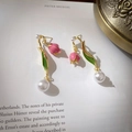 Detalle de pendientes de tulipán con esmalte rosa y perlas blancas sobre un libro de arte - Pin de Plata - Pendientes de Tulipán en Contraste