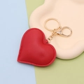 Close-up of red PU leather heart keychain with gold ring on beige display tray - Gold Chain Clasp / Red