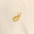 Polished gold stainless steel letter O pendant on textured beige fabric background - Letter-O
