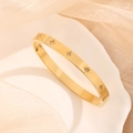 Armreif aus Titanstahl mit Sternmuster und Zirkonia auf einer Keramikplatte präsentiert - 2262 Achtzackiger Stern Zirkonia Armband / Gold