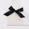 Detail of white wedding favor box with black ribbon and gold thank you lettering - White Box + Black Ribbon