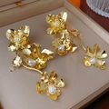 Detailed view of golden flower earrings with pearls resting in a professional jewelry box - 925 Silver Pin Flower Earrings / Gold