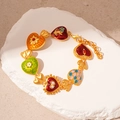 Close-up of vintage gold heart charm bracelet with colorful enamel inlay and pearls - Colorful Heart Bracelet