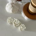 Elegant white triple rose hair claw clip on a minimalist white desk with decor - White