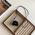 Detail view of mini black leather bag pendant with gold snap on wood jewelry tray - Black Leather Bag Style