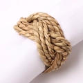 Close-up of woven rattan napkin ring with natural plant fiber texture on white napkin - Straw Woven Knot Style