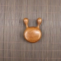 Close-up of polished sandalwood meridian massage tool with five teeth on bamboo mat - Golden Sandalwood Round Nose Scraper (6.5*4.3*1.8cm)