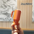 Handheld view of a mini 2oz orange tumbler with straw showing 60ml scale size - 2oz/60ml / Orange