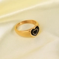 Detail of 18K gold stainless steel ring with black heart design on beige silk cloth - Black