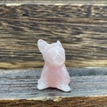 Miniature pink quartz crystal French bulldog figurine on a dark wood background - Rose Quartz