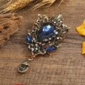 Spilla vintage in bronzo con cristalli blu su fondo in legno rustico - Stile di Fuoco