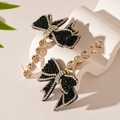 Dettaglio di orecchini a fiocco nero con strass e eleganti nappe di cristallo lucido - Nero (Perno per orecchino in argento)