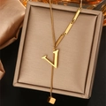 Detailopname van gouden V-letter ketting met kwastje en kubus op bruine juwelendoos - Letter V (WY006-V)
