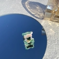 Détail d'une mini pince à cheveux ours en acétate marbré vert sur une surface miroir - Ours Glace Menthe