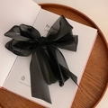 Elegant black organza bow banana clip for high ponytail on a book background - Black Chiffon Bow