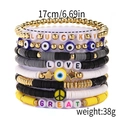 Detail of stacked handmade bracelets featuring polymer clay beads and golden lucky charms - LUCKY & LOVE Polymer Clay Bracelet Set
