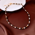 Détail d'un collier de perles en œil de tigre sur un tissu en satin marron luxueux - Perles Multicolores (Or/Marron/Blanc)