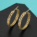 Makroaufnahme goldener Creolen im Panzerketten-Design mit glitzernden Zirkonia-Steinen - Panzerkette Stil / Gold