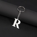 Polished silver stainless steel letter R keychain on textured black leather background - Letter R