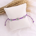 Detail of a purple woven bohemian bead bracelet on a white cushion with dried wheat decoration - Purple