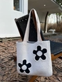 Close-up of beige knitted tote bag with black flower patterns hanging on wooden chair - Apricot