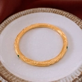 Detail of 18k gold plated ring bracelet with green stone inlay on ceramic tray - Gold