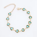 Detailed top view of a gold-plated bracelet featuring ten heart-shaped blue crystals - Gold + Light Blue