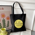 Detail of black oxford tote bag with yellow hello SUNSHINE print in a lifestyle setting - Black with Hello Sunshine Circle