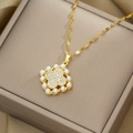Luxurious gold four-leaf clover necklace with white pearl and sparkling crystals on jewelry box - Necklace