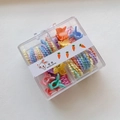 Detalle de gomas de pelo en espiral macaron y mini clips en una caja transparente - Mariposa
