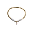 Detail of beaded gold bracelet with white pearls and a colorful zircon letter V charm - Letter V