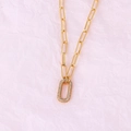 Vergulde schakelketting met rechthoekige diamanten hanger op roze papieren achtergrond - Ovale Gouden Ketting