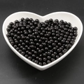 Glossy black round ABS imitation pearls in a white heart-shaped bowl with dark background - Black