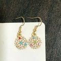 Detail of snowflake drop earring with colorful gemstones and white enamel in gold frame - Colorful Stone Snowflake