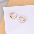 Dettaglio degli orecchini a cerchio in smalto beige e oro su supporto bianco - Nudo