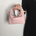 Detalle de bolso rosa de piel suave con elegante asa de perlas y herrajes dorados - Rosa
