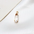 Macro shot of a teardrop-shaped glass pendant in a gold-plated copper claw setting - White