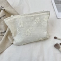 Détail de la broderie florale en dentelle blanche sur la trousse de maquillage - Beige
